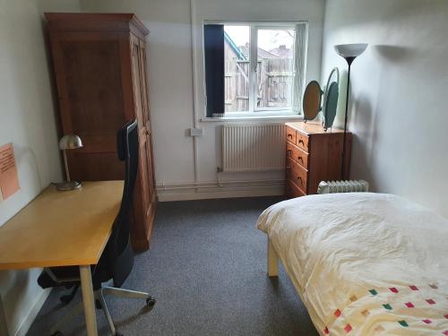 een slaapkamer met een bureau, een bed en een raam bij Dan's Homestay in Bristol