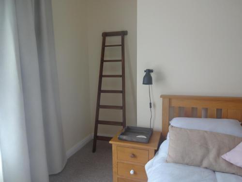 a bedroom with a ladder next to a bed at Rowan Cottage in Ottringham