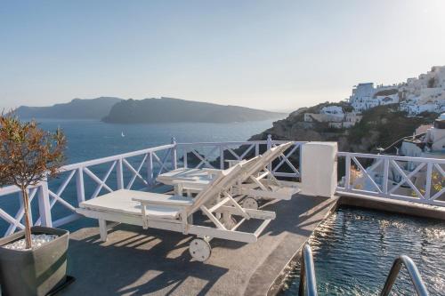 a deck with two lounge chairs on the water at Armeni Village in Oia