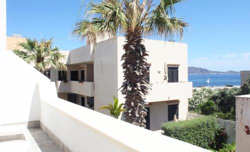 a view from the balcony of a white building with palm trees at Casa Maja rooms & suites in Favignana
