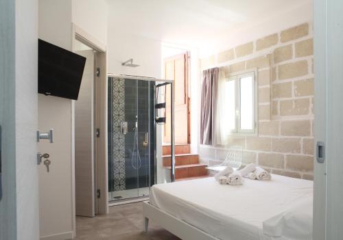 um quarto com uma cama branca e uma televisão em Casa Maja rooms & suites em Favignana