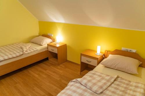 2 Betten in einem Zimmer mit gelben Wänden und 2 Leuchten in der Unterkunft Tourist Farm Rajšp in Benedikt v Slovenskih Goricah