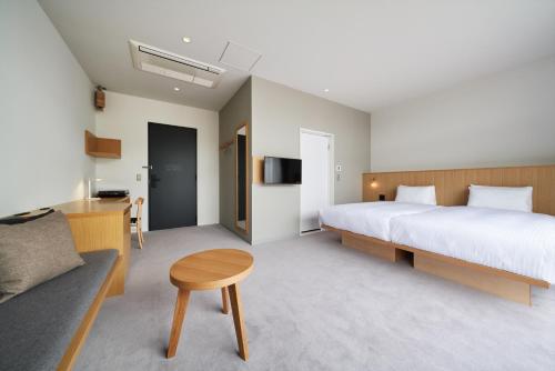 a bedroom with a bed and a table and a couch at MUSTARD HOTEL SHIMOKITAZAWA in Tokyo