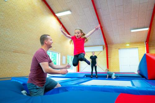a man and a girl jumping on an trampoline at SportsPark Blaavandshuk Resort in Oksbøl