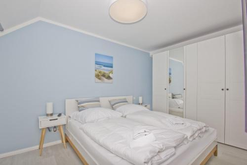 a bedroom with a large bed with white sheets at Ferienwohnung mit Meerblick und Gartennutzung - Haus Inselwind FeWo MEERstrand in Groß Zicker