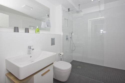 a white bathroom with a sink and a toilet at Ferienwohnung mit Meerblick und Gartennutzung - Haus Inselwind FeWo MEERstrand in Groß Zicker