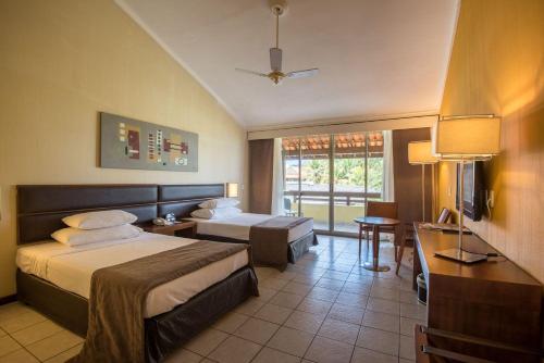 pokój hotelowy z łóżkiem, biurkiem i telewizorem w obiekcie Vila Galé Cabo - All Inclusive w mieście Cabo de Santo Agostinho