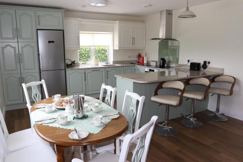 a kitchen with a wooden table and a kitchen island at Laneside Haven - 5 Minutes from Castleblayney - Accessible, Gated with Patio, Garden and Gym! in Monaghan