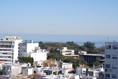 uma cidade com edifícios brancos e o oceano no fundo em Penthouse Malva Rosa em Montevidéu