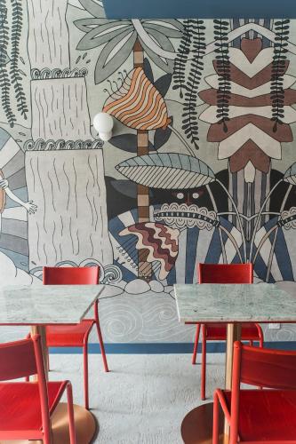 a room with two tables and chairs and a mural at Hôtel-Spa Ô Rouge - Gevrey-Chambertin - Teritoria in Gevrey-Chambertin