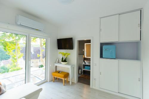 a living room with white cabinets and a yellow stool at MintaMókus Vendégház in Miskolctapolca