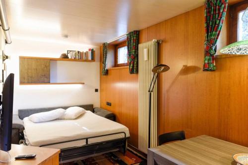 1 dormitorio con cama, escritorio y mesa en Bilocale a 1 minuto dalle piste da sci di Bormio, en Bormio