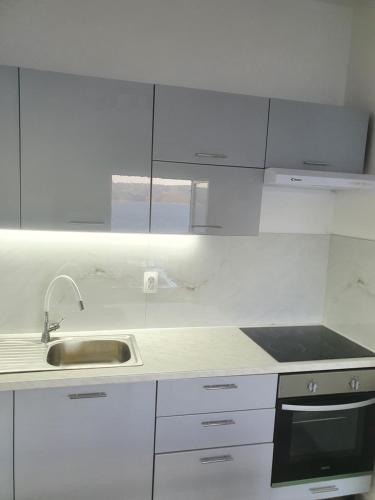 a kitchen with white cabinets and a sink at Apartment ZaDoDa in Omiš