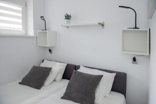 a room with a bed with two pillows and two lights at Apartament u Mirki in Puck