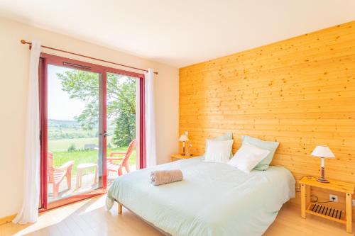 a bedroom with a bed and a large window at Le Pré devant nous in Picherande
