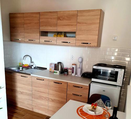 mała kuchnia z drewnianymi szafkami i kuchenką mikrofalową w obiekcie Grkov Apartment w mieście Skopje
