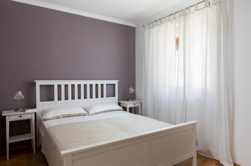 a white bedroom with a white bed and a window at Apartments Silvija in Mokošica