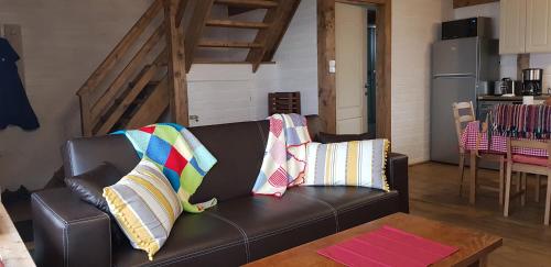 a living room with a leather couch with pillows on it at Casuta de Vacanta Marisel, Cluj in Mărişel