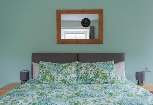 a bedroom with a bed with a mirror above it at Altquhur Byre in Drymen