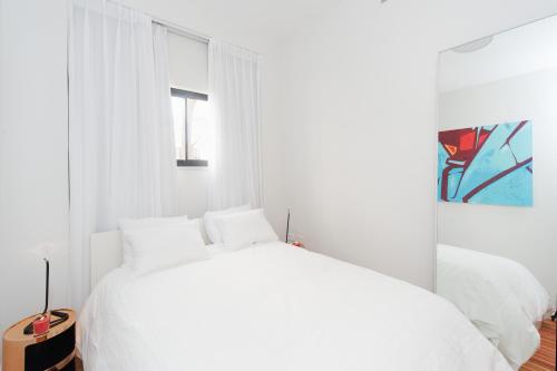 a white bedroom with a white bed and a window at Hilton Beach by Five Stay in Tel Aviv