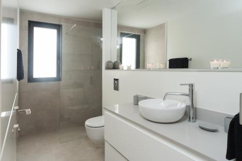 a white bathroom with a sink and a toilet at Hilton Beach by Five Stay in Tel Aviv