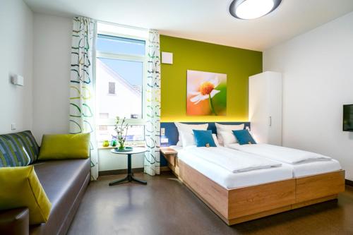 a bedroom with a bed and a couch and a window at Hotel Leib & Seele in Drensteinfurt