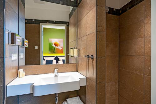 uma casa de banho com um lavatório e um espelho em Hotel Leib & Seele em Drensteinfurt