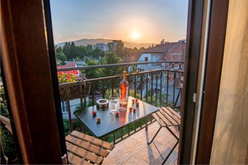 a table on a balcony with a view of the sunset at Family Hotel Konstantinovi in Kyustendil