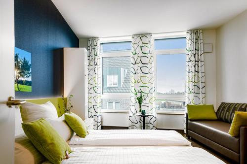 a bedroom with a bed and a couch and windows at Hotel Leib & Seele in Drensteinfurt