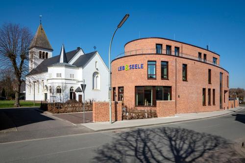 a brick building on the corner of a street with a church at Hotel Leib & Seele in Drensteinfurt