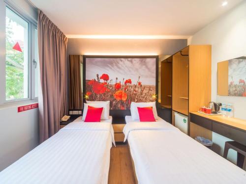 a room with three beds with red pillows at Hi Hotel Dot in Singapore