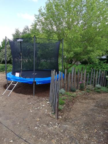 a blue trampoline in a yard next to a fence at LA MAISON D'ALIDA in Nueil-sous-Faye