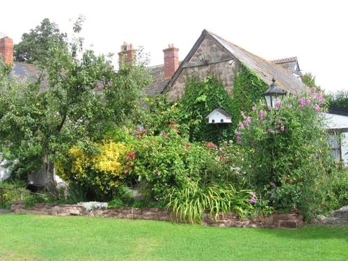 a house with a bunch of flowers in a yard at Steps Farmhouse B&B in Minehead