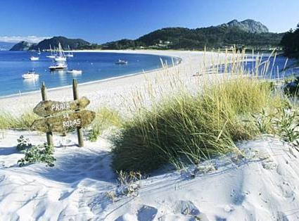 a beach with a sign in the sand and water at Casa Independiente Bella Vista in Moaña