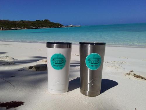 two cups sitting on the beach near the ocean at Da Sugar House in Georgetown