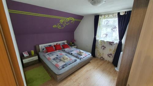 Dormitorio pequeño con cama y pared púrpura en Apartment Tijana, en Nomenj