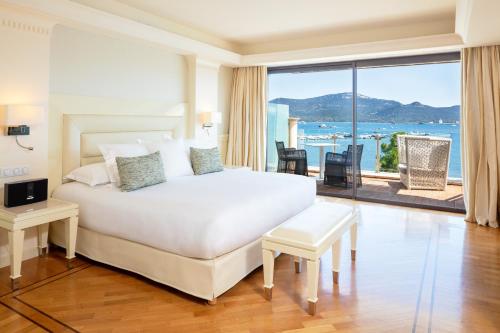 a bedroom with a large white bed and a large window at Hotel Don Cesar in Porto-Vecchio