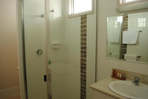 a bathroom with a glass shower and a sink at David Motor Inn in Rockhampton