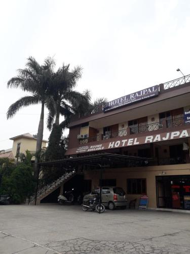 ein Hotelgebäude mit einer Palme davor in der Unterkunft Hotel Rajpal Guest House in Dehradun