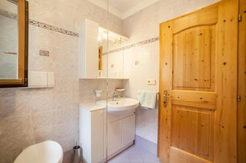 uma casa de banho com um lavatório e uma porta de madeira em Sonnenparadies Apartement 1 em Saltusio