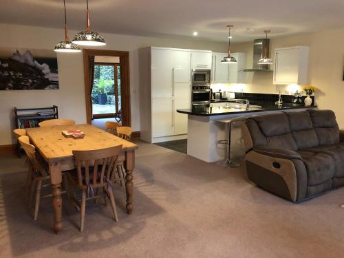 a kitchen and living room with a table and a couch at The Burrow at Woodlands in Newquay