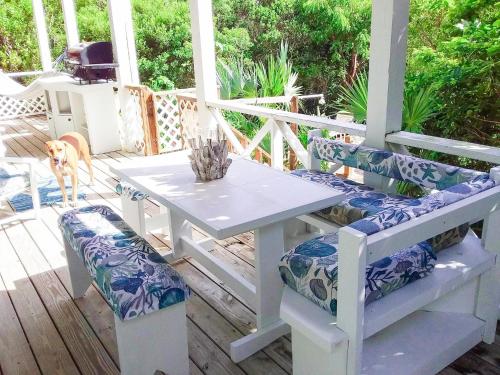 a white table and chairs on a porch with a dog at Da Sugar House in Georgetown