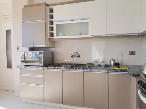 una cucina con armadi bianchi e ripiani in granito di Hostal Costa De Marfil Suites & Apartamentos a Cochabamba