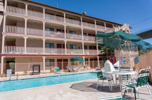 un hotel con piscina, mesas y sillas en Heritage Inn La Mesa, en La Mesa