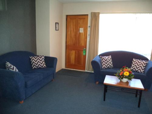 a living room with two blue couches and a table at South Park Motel in Masterton