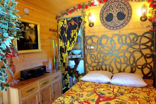 a bedroom with a bed in a wooden room at La Ferme De Chenevier, La Roulotte Fleurie 2/4pers in Saint-Victor