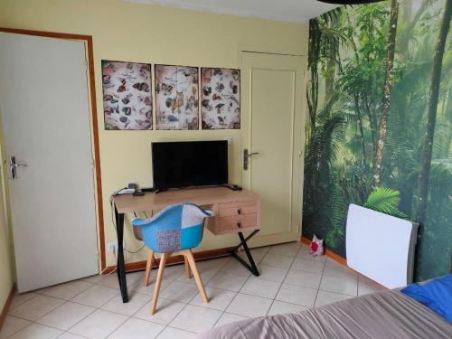 a bedroom with a desk with a television and a chair at chambre avec SDB privative en pleine campagne in Baillou