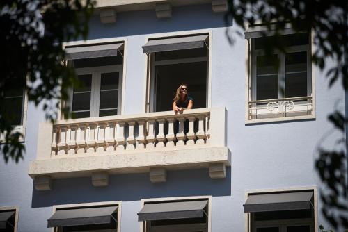 a woman sitting on a balcony looking out of a window at PortoBay Marquês in Lisbon