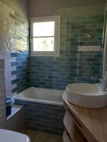 a bathroom with a sink and a tub and a window at Hotel Mendionde in Saint-Pée-sur-Nivelle