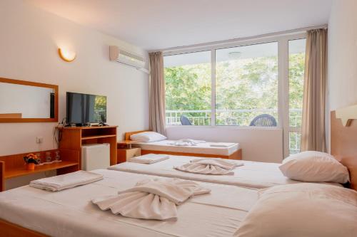 een hotelkamer met 2 bedden en een raam bij Хотел Ескана in Shkorpilovtsi